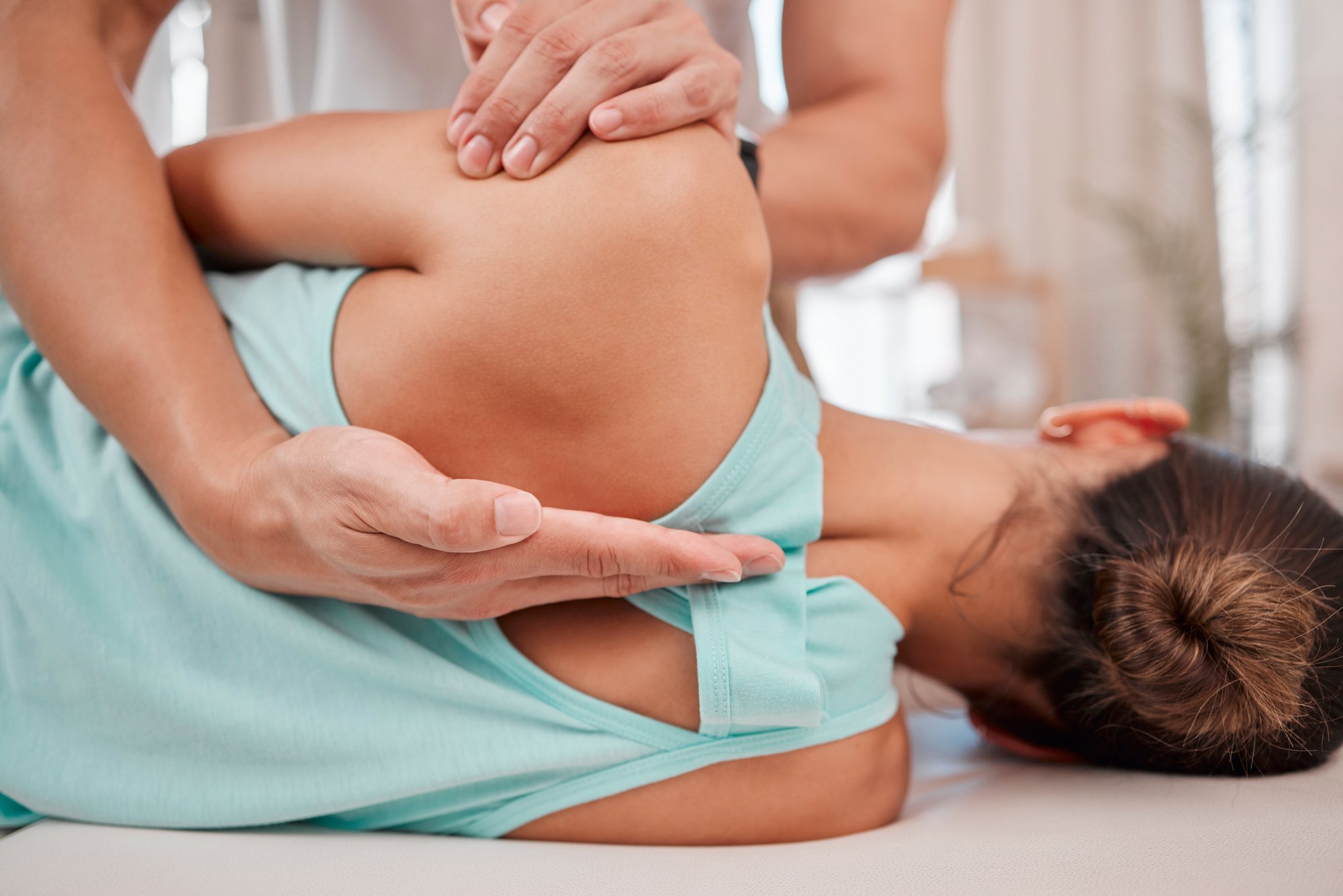Physiotherapeut behandelt Patientin Physiotherapeut bei der Behandlung einer Patientin, Fokus auf den Schulterbereich.